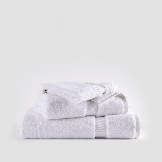 White bamboo towel set stacked neatly showing face, hand, and bath towels with textured bands against neutral background.