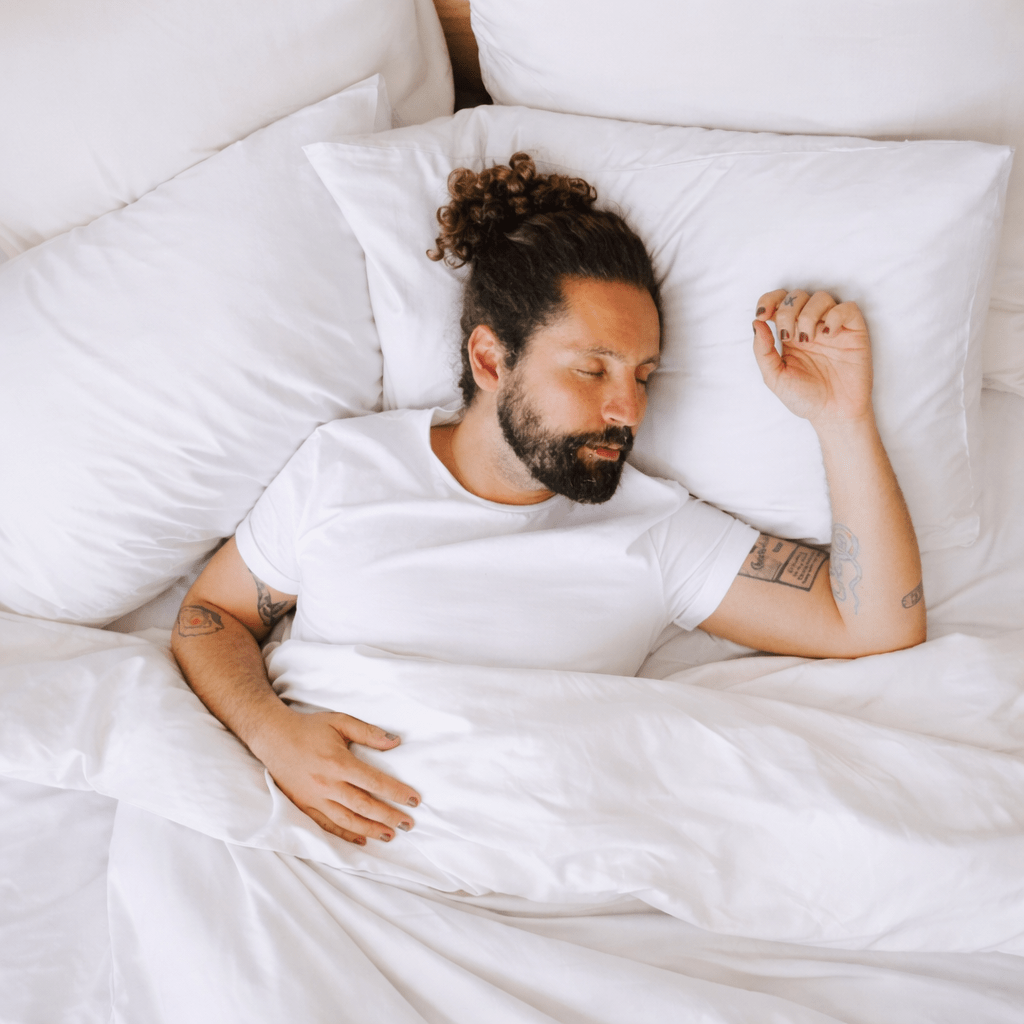 Man sleeping comfortably on white hypoallergenic bamboo sheets