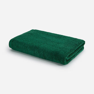 Forest green bath towel folded on white background, Wabi-sabi design by Momo Cotton