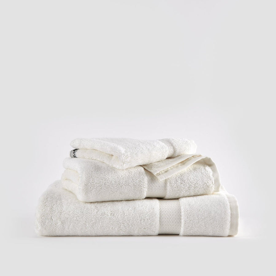 Stacked white bamboo towel set with face, hand, and bath towels on neutral background