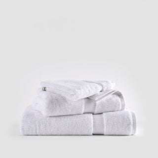 White bamboo towel set stacked neatly showing face, hand, and bath towels with textured bands against neutral background.