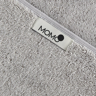 Gray bamboo towel with momo-cotton brand label on white trim, close-up of soft texture