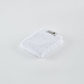 White bamboo towel with Momo Cotton label on light background, angled view