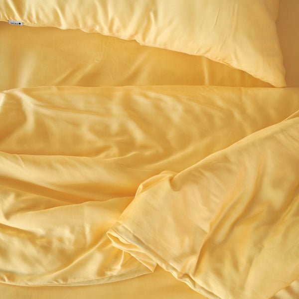Cream bamboo bedding set with pillows and duvet cover folded, showing soft fabric texture and quality weave