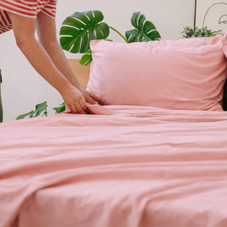 Hands holding pink bamboo fabric, highlighting its lightweight, silky texture.